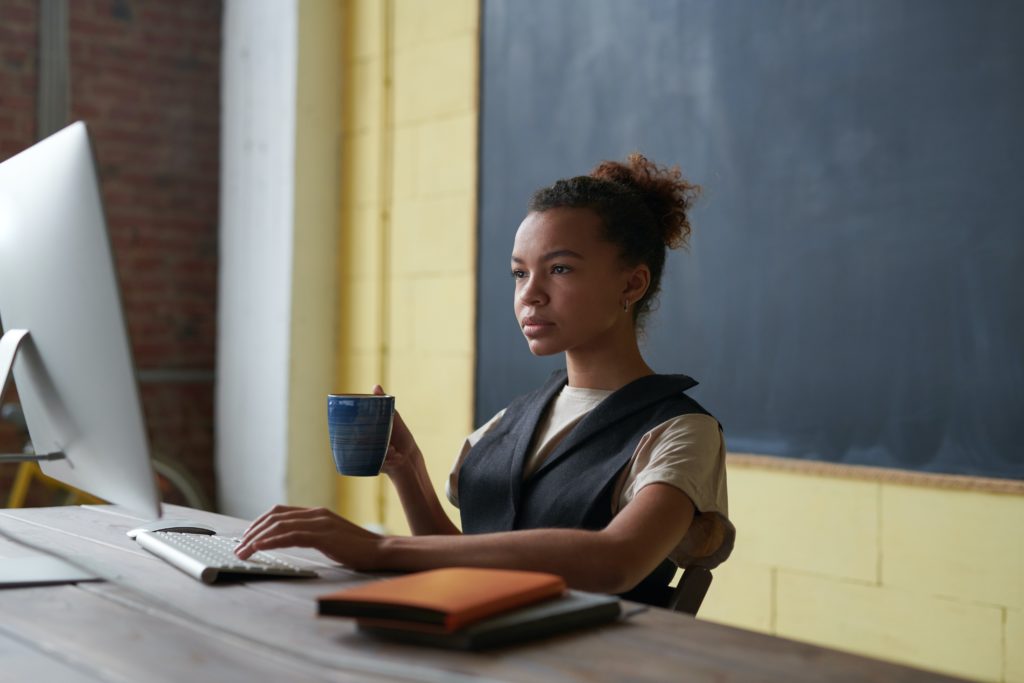 teacher on computer in front of blackboard